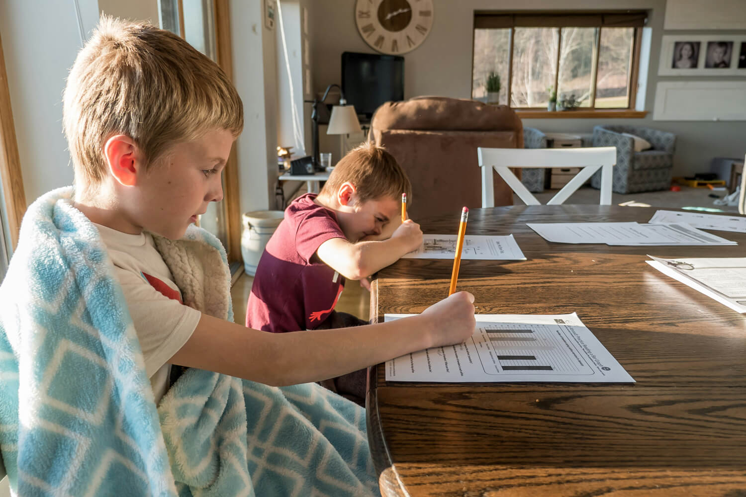 Photo of two boys working on homework at a kitchen table at home.