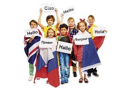 Photo of a group of young children holding up signs that say hello in various languages, such as hello, hallo, hola, ciao, and bonjour.